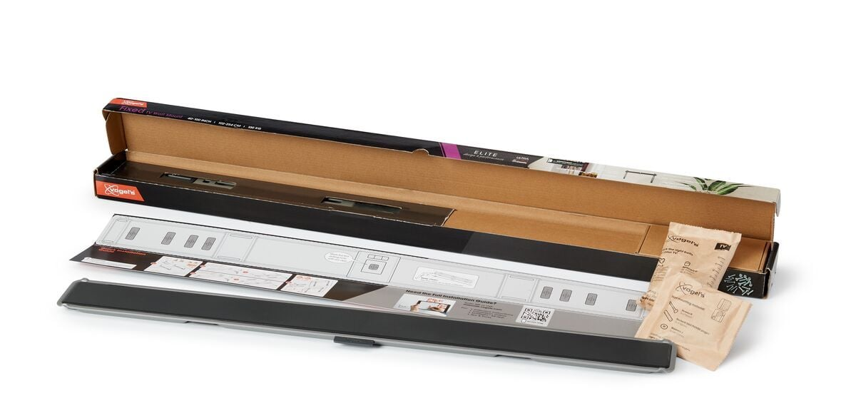 Otwarta skrzynka z zestawem do montażu ściennego TV. Zawiera uchwyt, instrukcje i małe paczki na białej powierzchni.