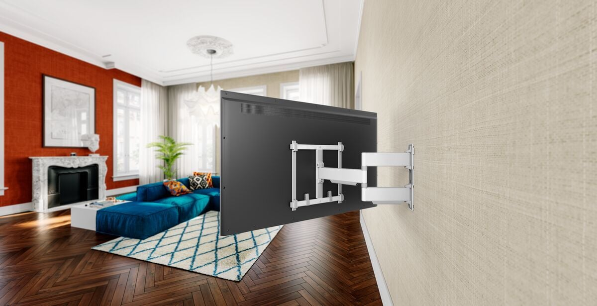 Salon z telewizorem na uchwycie ściennym, niebieską sofą, dywanem i kominkiem. Czerwona ściana i drewniana podłoga.