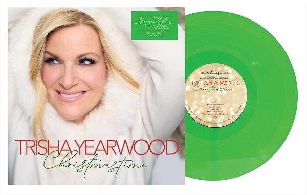 Trisha Yearwood Album 'Christmas Time' und grüne Schallplatte. Yearwood lächelt in weißem Mantel. Albumcover und Vinyl sichtbar.