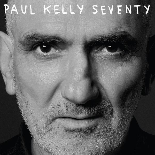 Nahaufnahme eines älteren Mannes in Schwarzweiß. Titel oben: Paul Kelly Seventy. Mann hat kurze Haare, Bart und fokussierte Augen.