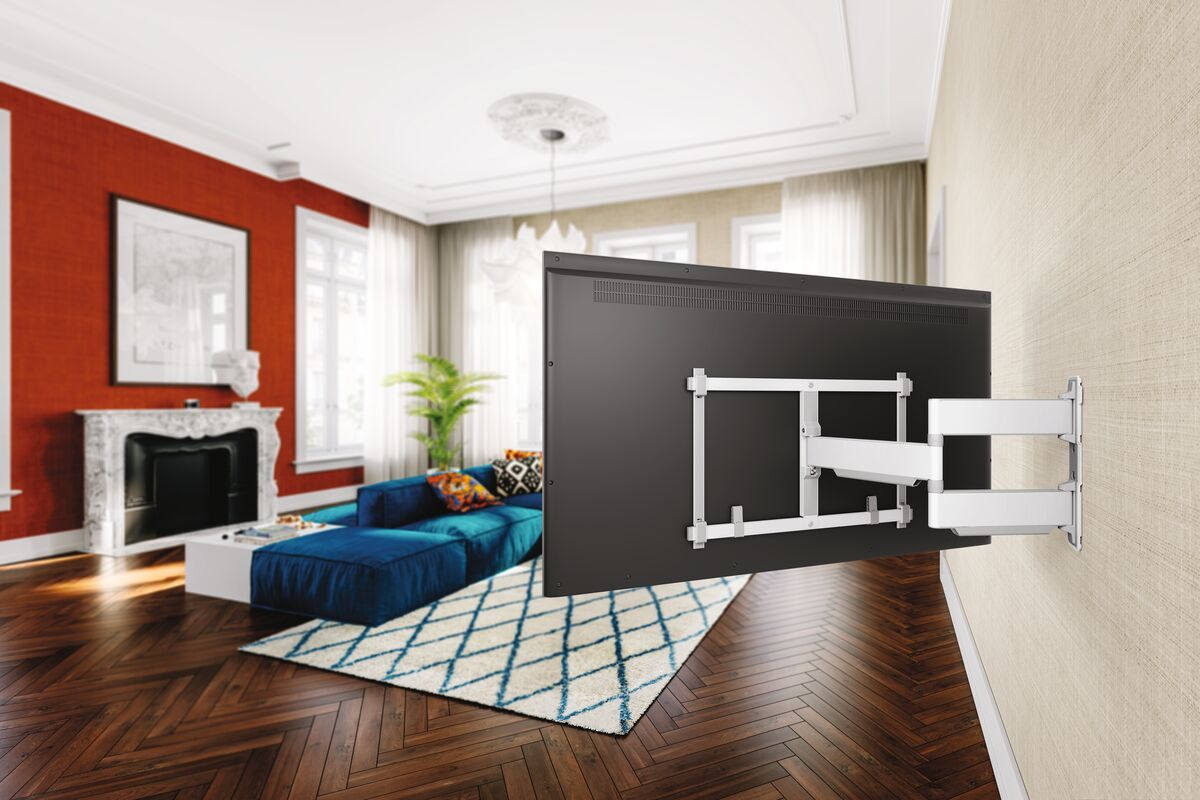 Salon z telewizorem na uchwycie ściennym. Widoczna niebieska sofa, dywan, czerwona ściana, kominek i podłoga.