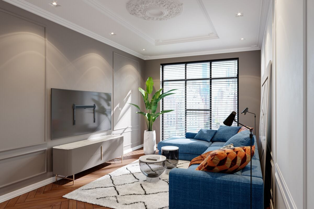 Salon z niebieską sofą narożną, białym dywanem i dużym oknem z żaluzjami. Telewizor jest zamontowany na ścianie.