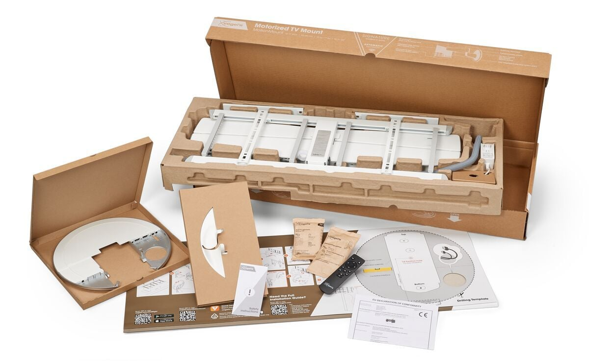 Otwarta skrzynia uchwytu TV z częściami. Zawiera uchwyt, pilota, papiery i wspornik. Wszystko jest białe i brązowe.