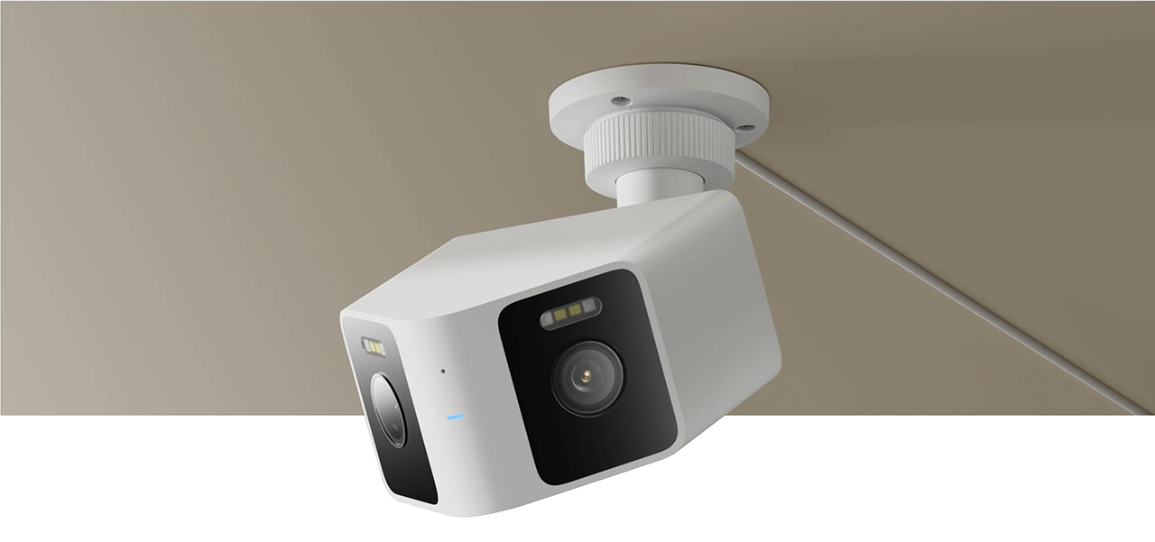 Biała kamera bezpieczeństwa zamontowana na suficie. Ma obiektyw i jest podłączona do białego kabla.