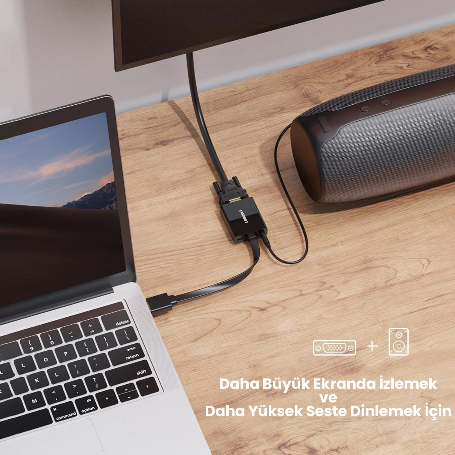 Siyah bir adaptör aracılığıyla bir monitöre ve hoparlöre bağlı bir dizüstü bilgisayar. Kurulum ahşap bir masada.