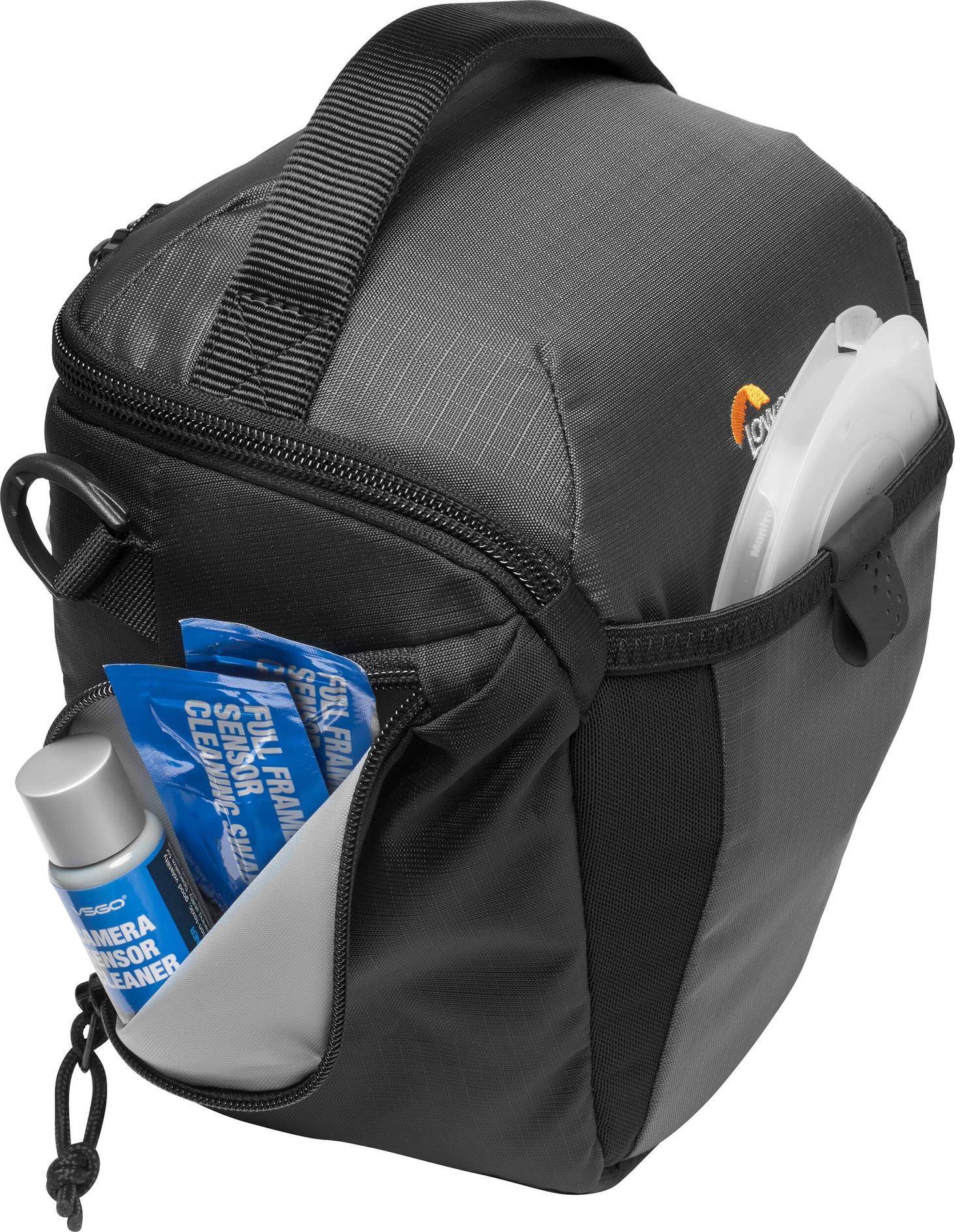 Borsa per fotocamera nera con prodotti per la pulizia e un accessorio bianco. La borsa ha un manico e una tasca laterale.
