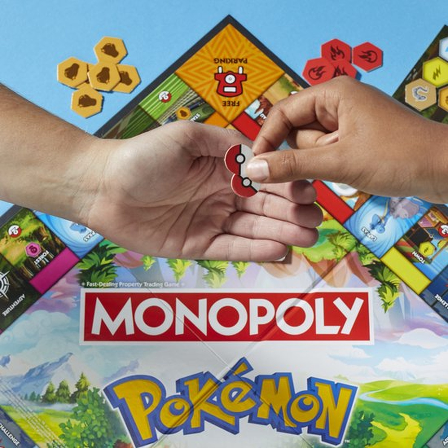 Handen houden spelstukken boven een Pokémon Monopoly-bord. Bord toont spelvakken en logo's. Zeshoekige tokens zijn ook zichtbaar.