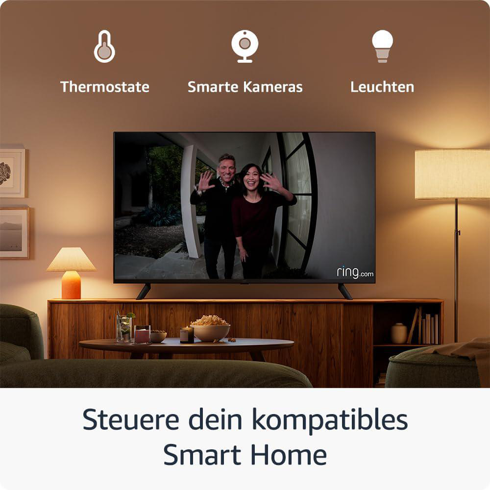 Ein Fernseher zeigt ein winkendes Paar. Darunter steht: 'Steuern Sie Ihr kompatibles Smart Home.' Symbole für Thermostat, Kameras und Lichter.