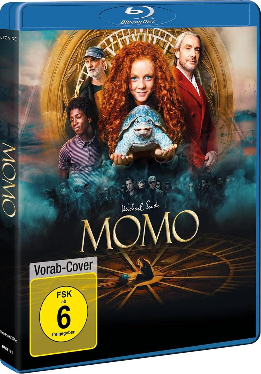 Blu-ray-Cover des Films 'Momo'. Zeigt ein Mädchen mit roten Haaren, das eine Schildkröte hält. Im Hintergrund sind mehrere Personen zu sehen.