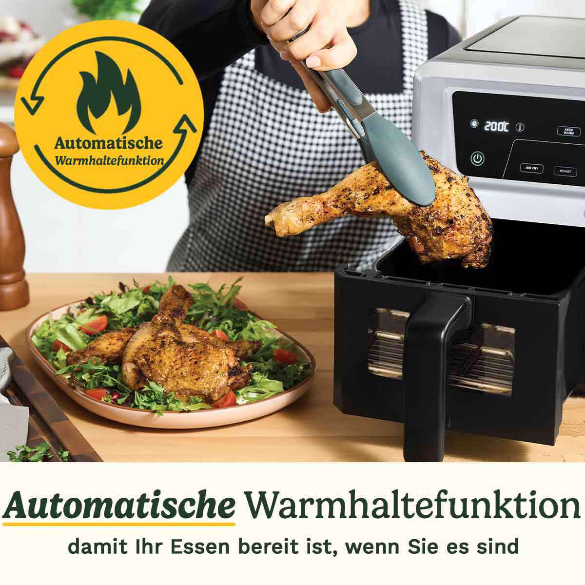 Eine Person legt mit einer Zange ein gekochtes Hähnchenbein in eine Heißluftfritteuse. Salat und Text im Vordergrund.