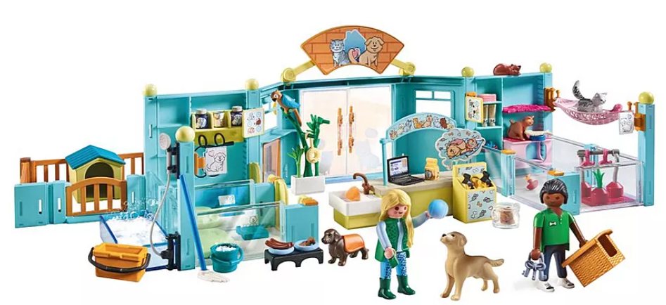 Ein Playmobil-Tierklinik-Set mit Figuren, Hunden, Katzen und Zubehör wie einem Laptop und Futternäpfen in einem blauen Gebäude.