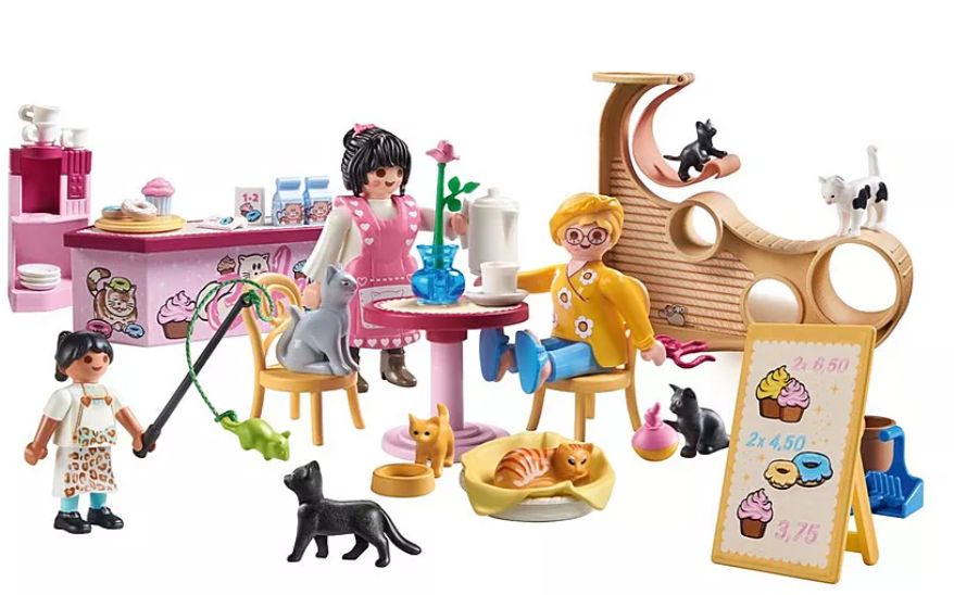 Eine Playmobil-Katzencafé-Szene. Figuren interagieren mit Katzen, einer Theke mit Gebäck, einem Katzenbaum und einer Preisliste.