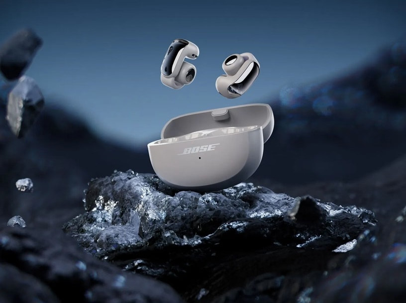 Słuchawki Bose i etui ładujące na ciemnej skale. Słuchawki unoszą się nad etui. Tło jest ciemne i rozmyte.