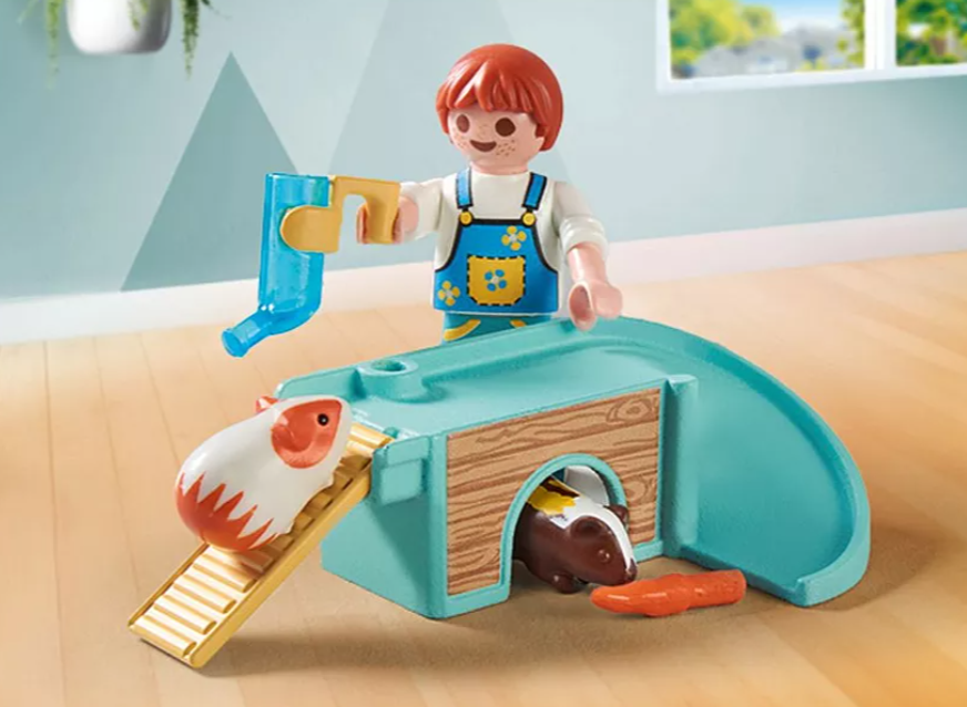 Eine Kinderfigur mit einem Wasserspender und einem Meerschweinchen-Spielzeugset. Zwei Meerschweinchen, eines weiß und rot, das andere braun, sind sichtbar.