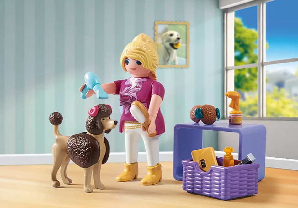 Eine Playmobil-Hundefriseurszene. Eine Frau pflegt einen Pudel. An der Wand hängt ein Bild eines Hundes, auf einem Tisch liegen Pflegeutensilien.