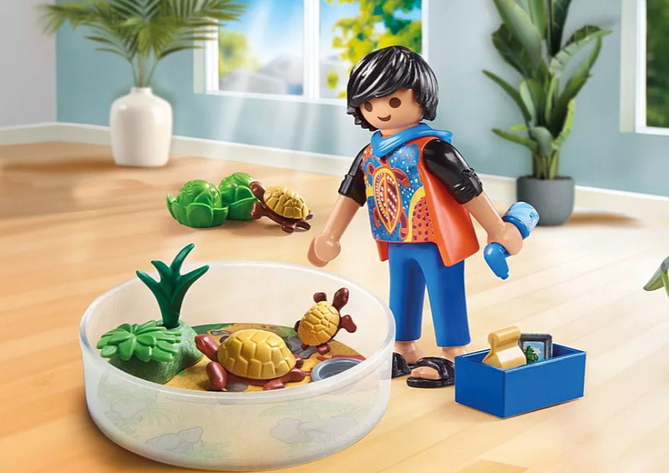 Eine Kinderfigur mit Spielzeugschildkröten und Zubehör. Das Kind steht neben einem Schildkrötenhabitat. Pflanzen sind im Hintergrund.