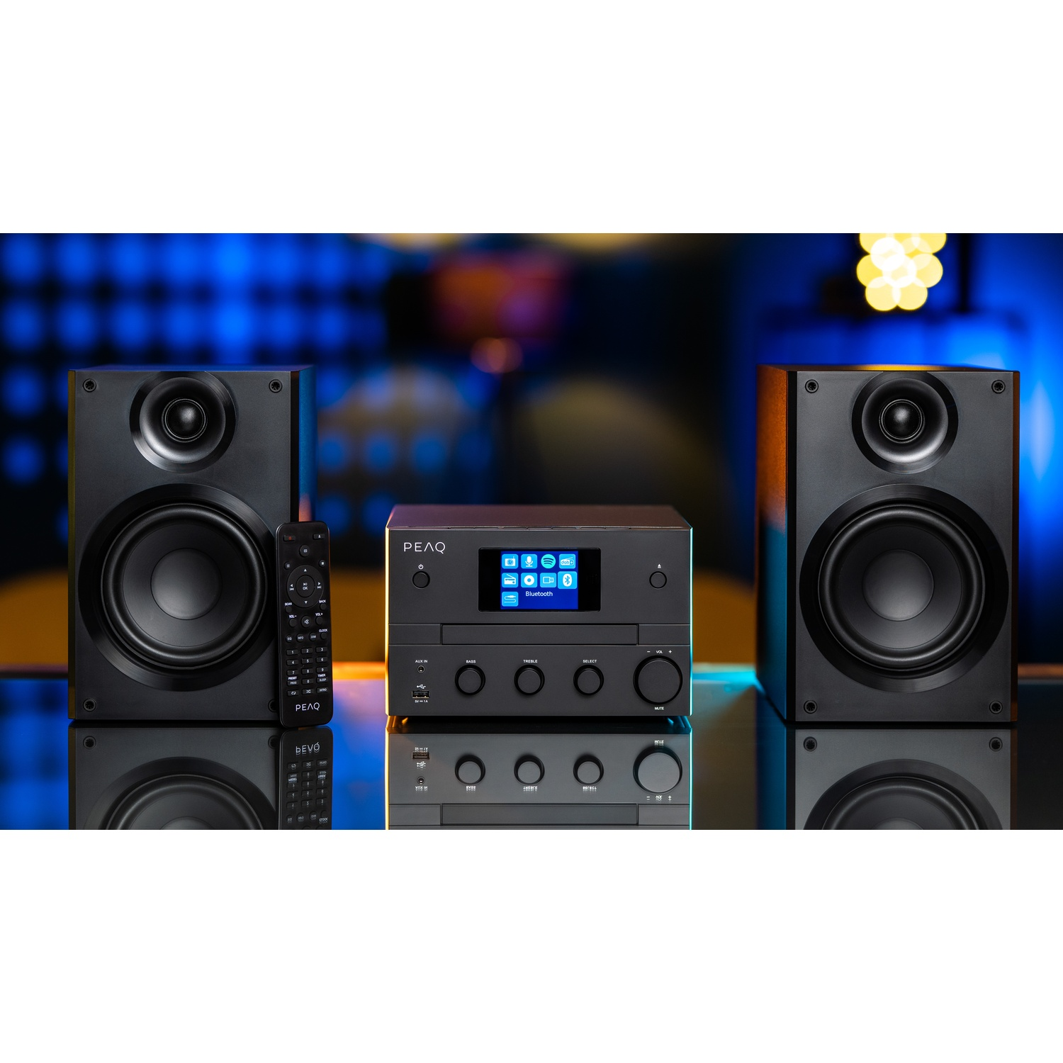Impianto stereo nero con altoparlanti su superficie riflettente, telecomando e sfondo blu brillante.