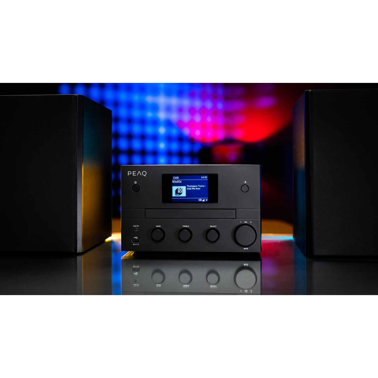 Impianto stereo nero con schermo che mostra informazioni musicali. Due altoparlanti neri fiancheggiano l'unità centrale. Sfondo con colori sfocati.