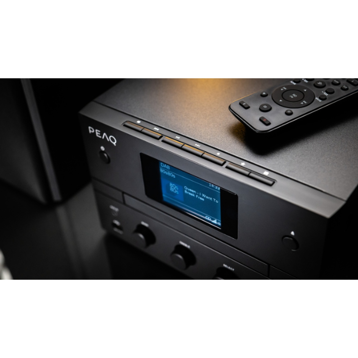 Sistema stereo PEAQ nero con telecomando. Il display mostra la stazione radio DAB e le informazioni sul brano. Telecomando in alto.
