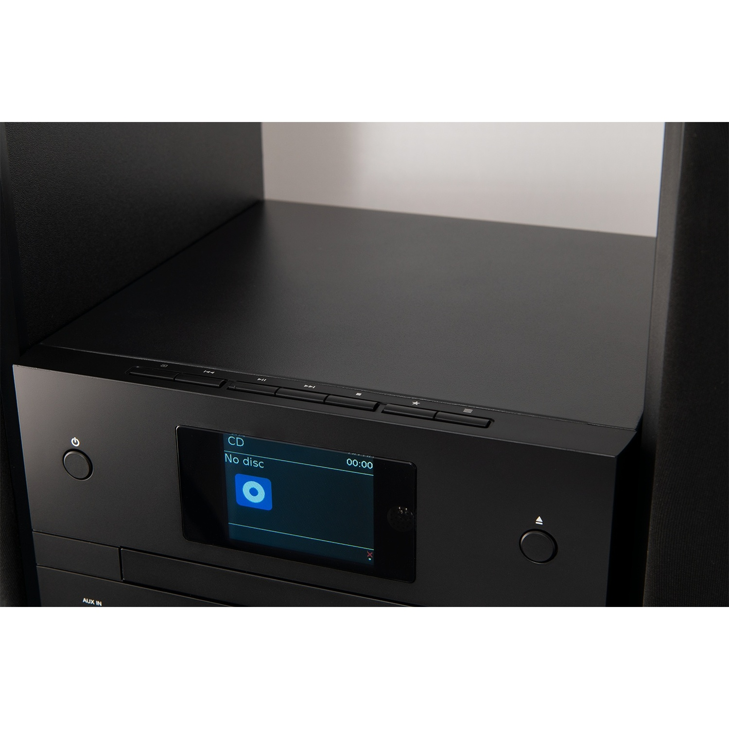 Un impianto stereo nero con display digitale che mostra 'No disc'. Il sistema è su una mensola, con altoparlanti ai lati.