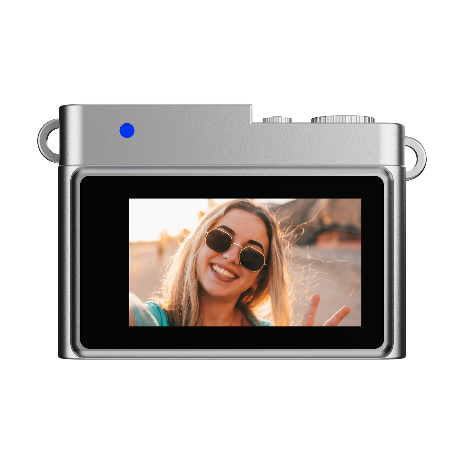 Una fotocamera argentata mostra un selfie di una donna bionda sorridente con occhiali da sole, che fa il segno della pace, con uno sfondo all'aperto.