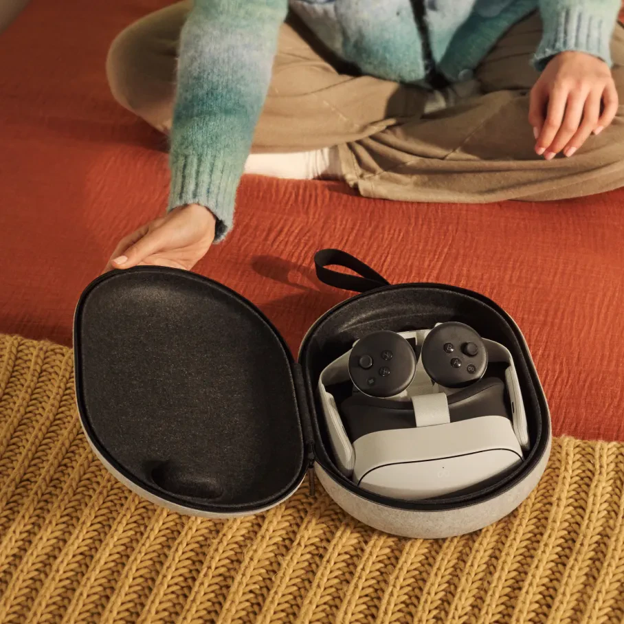 Eine Person öffnet einen VR-Headset-Koffer auf einem Bett. Der Koffer ist geöffnet und zeigt das Headset und die Controller.