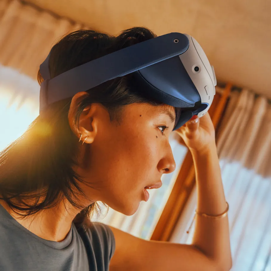 Eine Person mit VR-Headset. Die Person schaut mit ernstem Gesichtsausdruck nach unten. Das Headset ist weiß und blau.