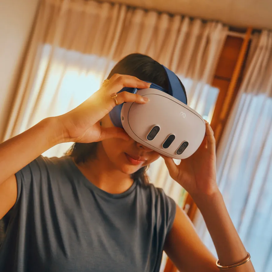 Eine Person trägt ein VR-Headset. Das Headset ist weiß und blau. Die Person trägt ein graues Hemd.