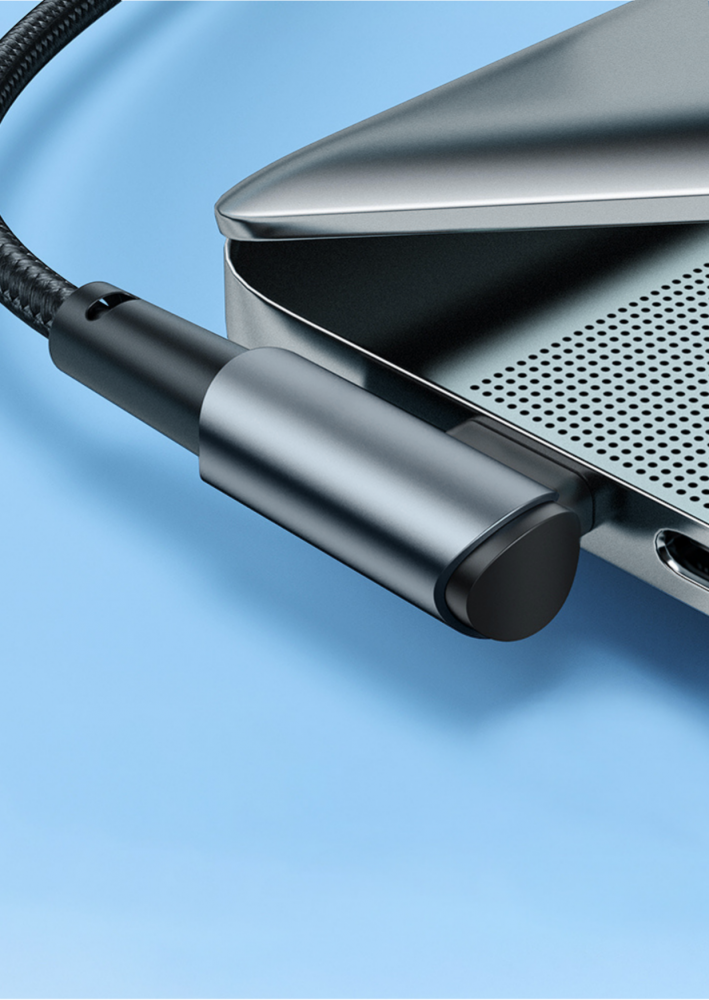 Egy laptop USB-C kábellel. A kábel fekete, a laptop ezüst. Kék háttér.