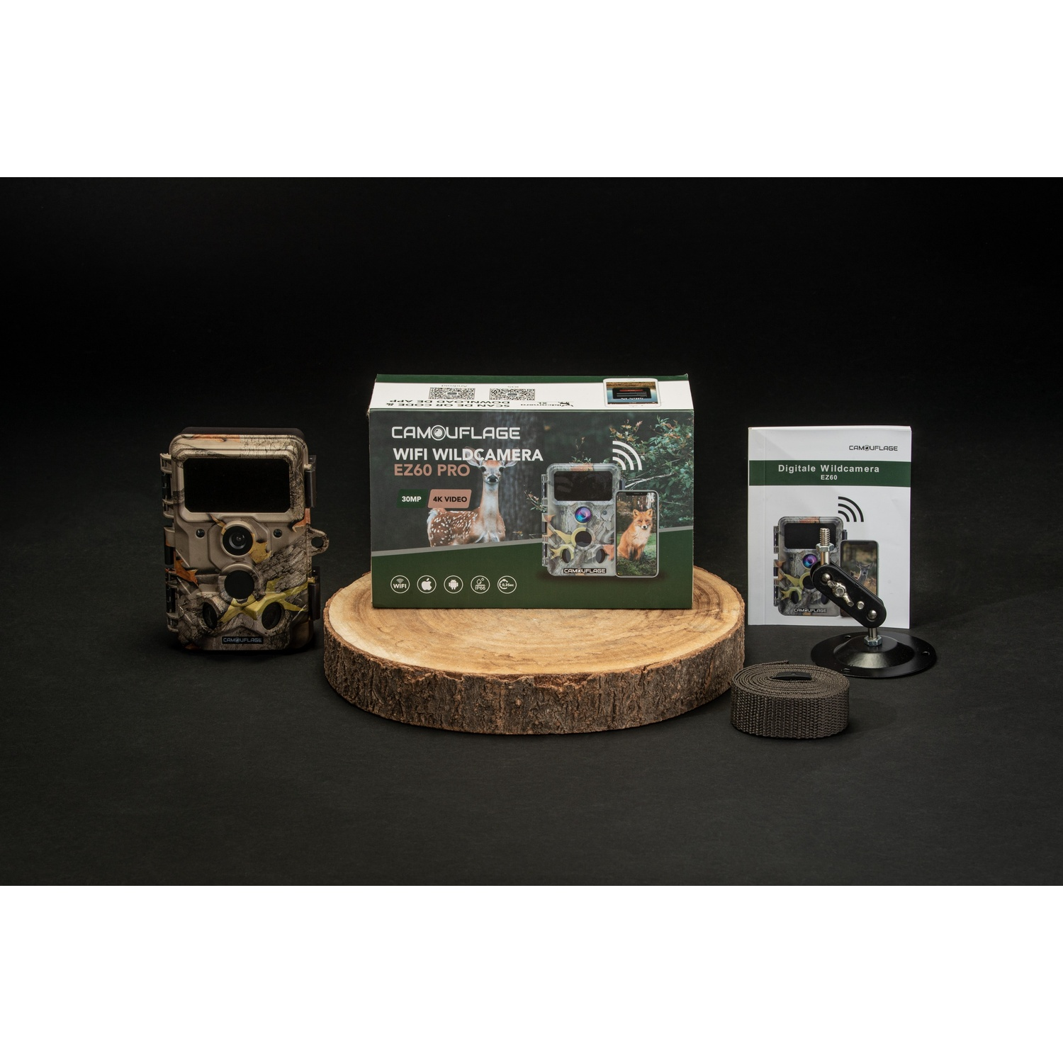 Un kit fotocamera naturalistica su una fetta di legno. Include una fotocamera, scatola, manuale, cinturino e supporto, tutto su una superficie nera.