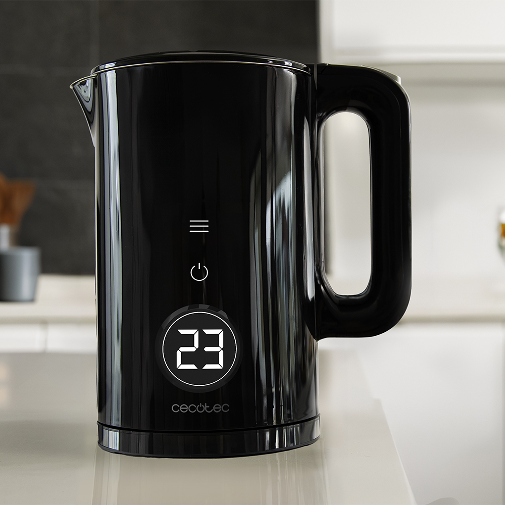 Una tetera eléctrica negra con una pantalla digital que muestra '23'. Tiene un asa y está sobre una superficie blanca. El fondo es una cocina.
