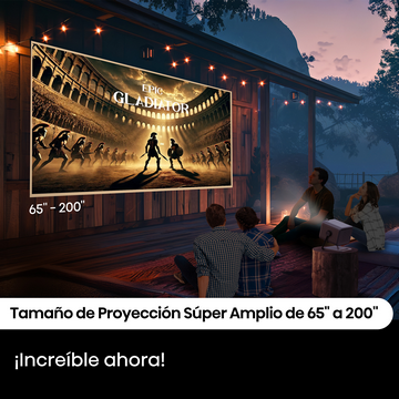 Personas viendo una película, "Gladiator", en una gran pantalla al aire libre por la noche. Luces y proyector visibles.