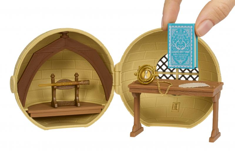 Ein Miniatur-Harry-Potter-Spielset. Es hat einen Zauberstab, einen Schreibtisch mit einer Sanduhr und einem Buch sowie eine Hand, die ein Buch hält.