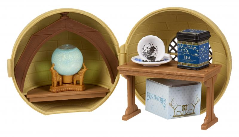 Ein offenes, rundes, gelbes Spielzeug mit einem Tisch. Auf dem Tisch eine Teetasse mit Teeblättern, eine Teebox und eine Wahrsagebox.