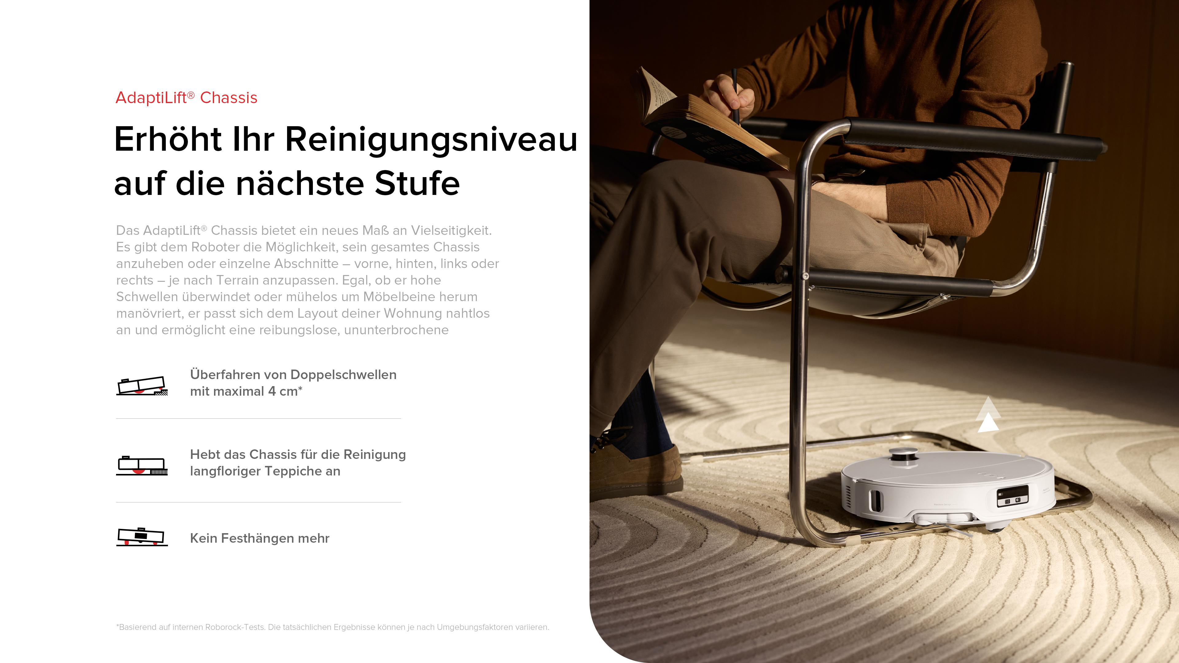 Eine Person sitzt in einem Stuhl und liest ein Buch, während sich ein Roboter-Staubsauger auf einem gemusterten Teppich befindet.