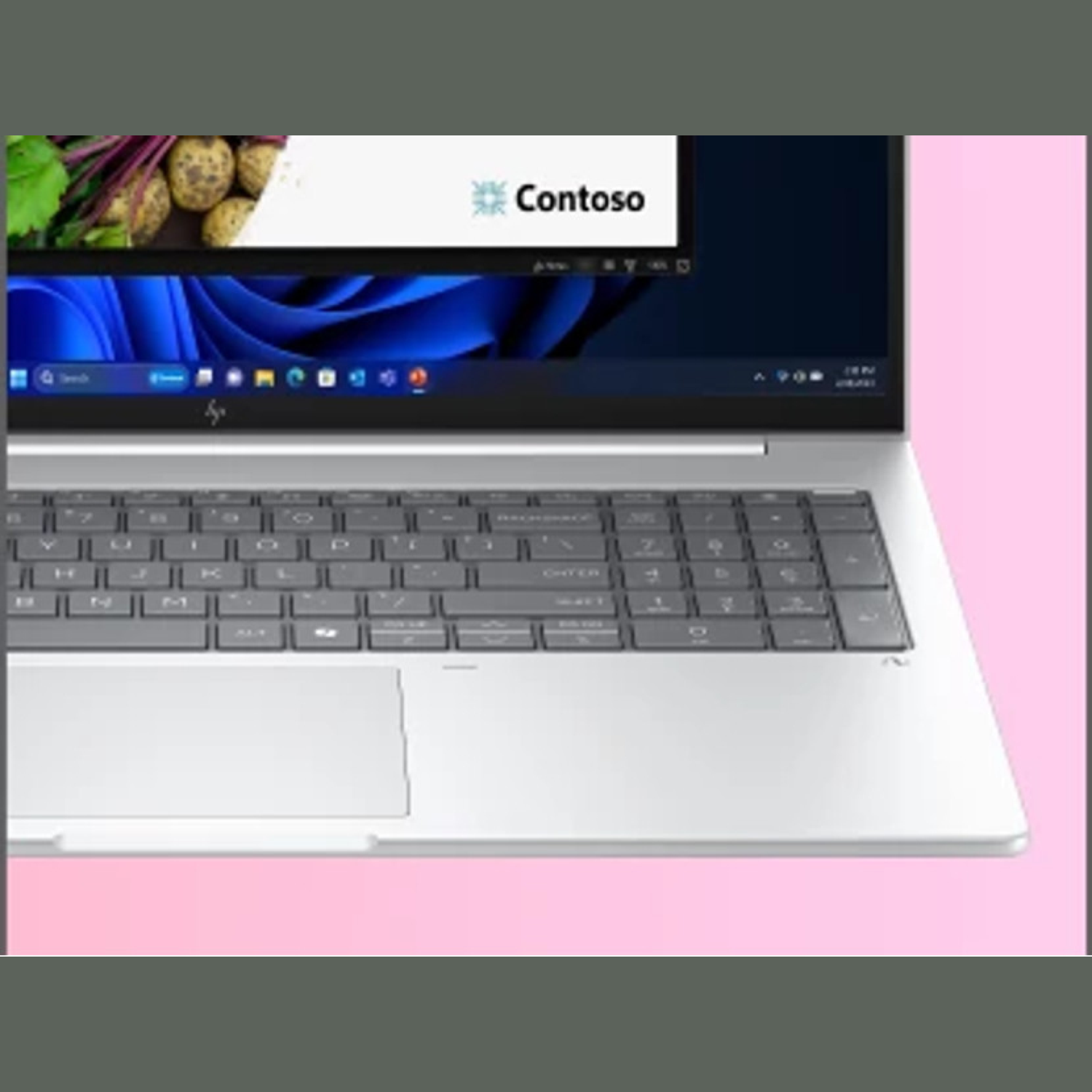 Laptop met toetsenbord en scherm met een presentatie. Het scherm toont het "Contoso"-logo en een foto van groenten.