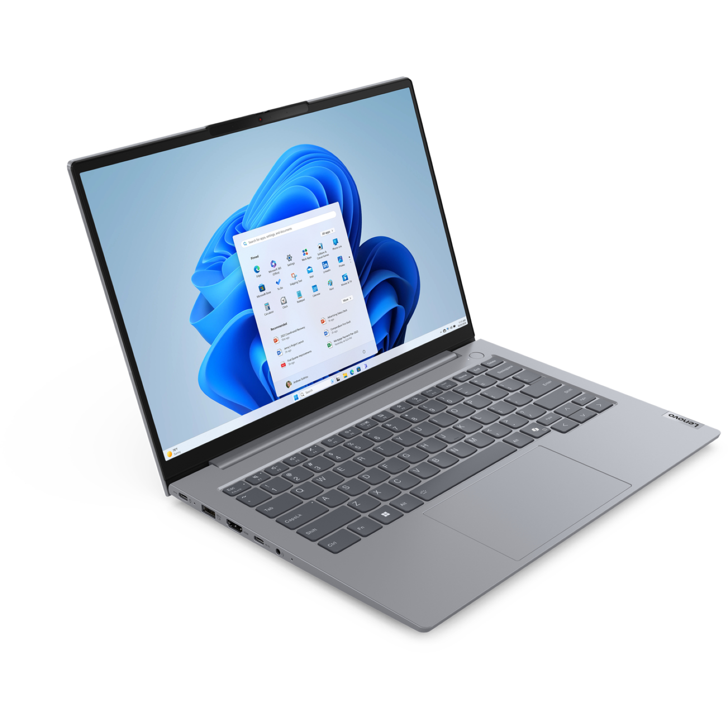 A silver Lenovo laptop is open, displaying a Windows 11 desktop with app icons. The keyboard is visible, with the Lenovo logo.