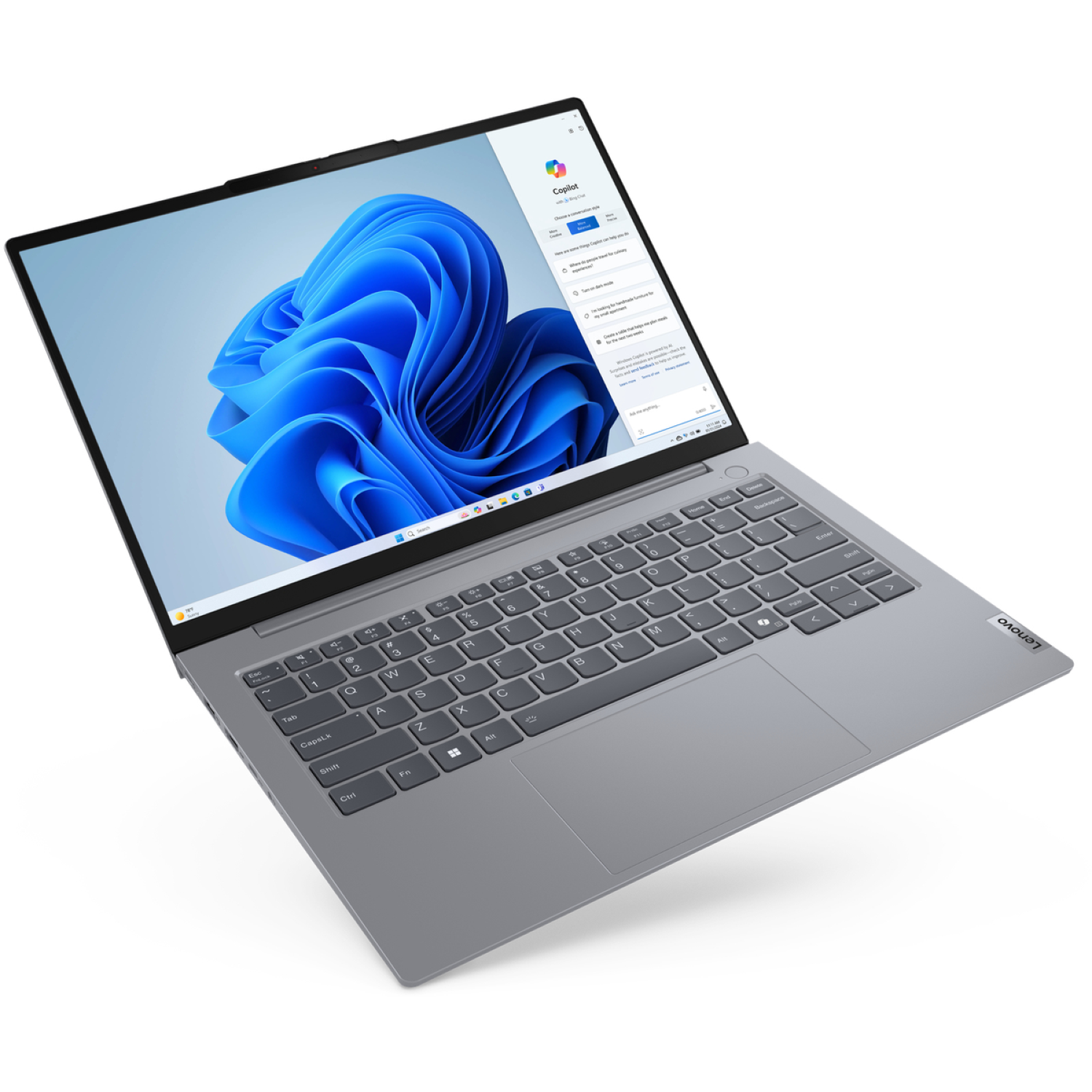 A Lenovo laptop, open, with a Windows 11 interface. The screen displays a cloud-like blue image and the Copilot app.