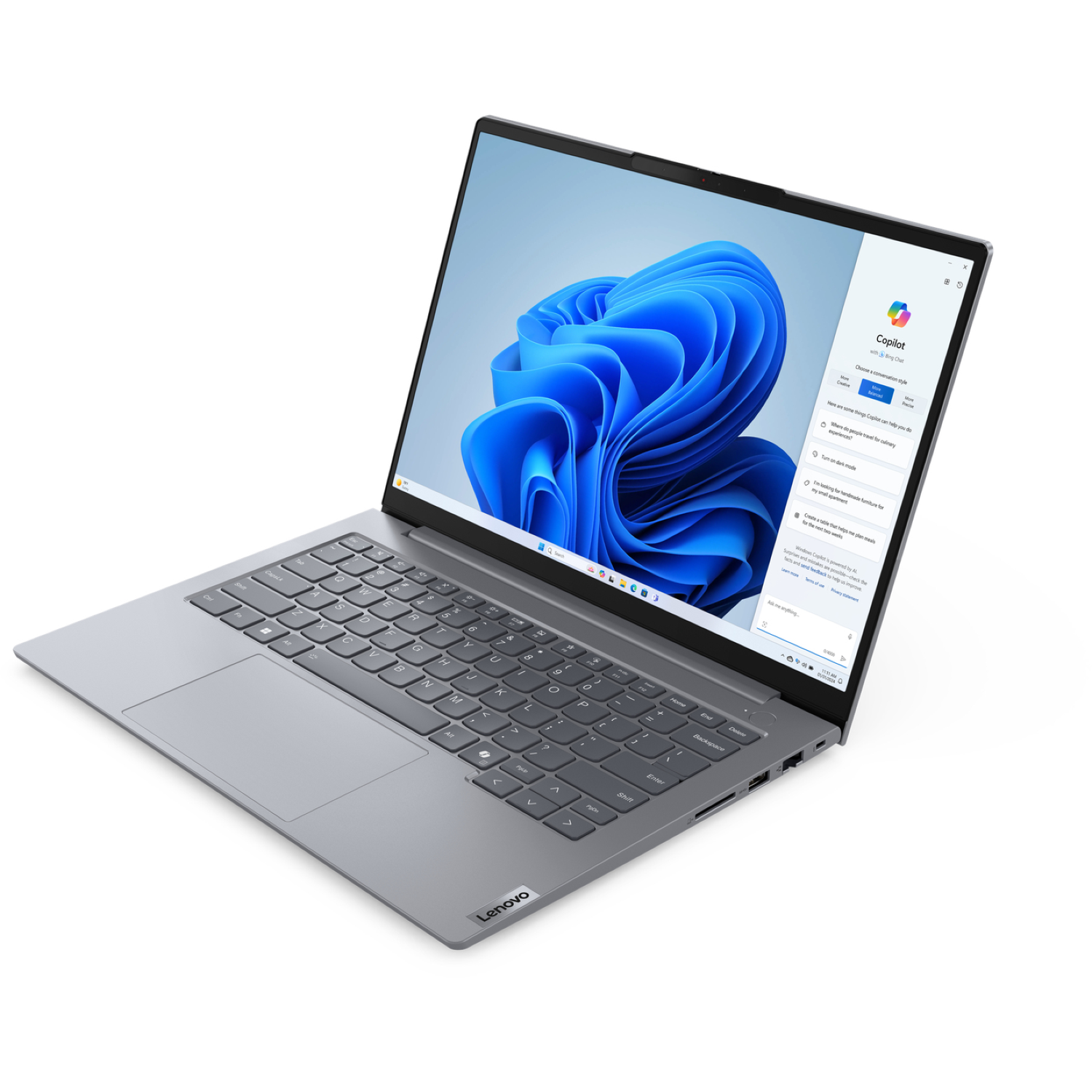 A gray Lenovo laptop is displayed on a white background. The screen shows the Windows 11 interface with a blue abstract design and Copilot.