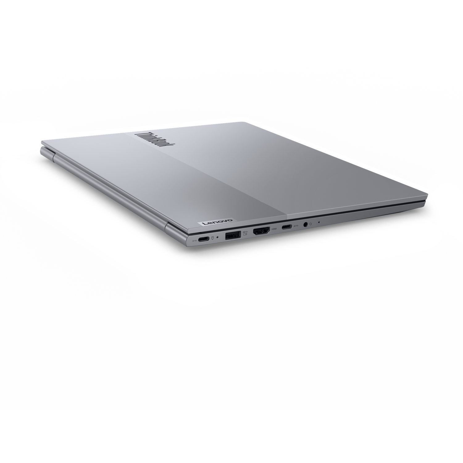 A closed silver Lenovo ThinkBook laptop on a white surface. The laptop is angled, showing the ThinkBook and Lenovo logos.