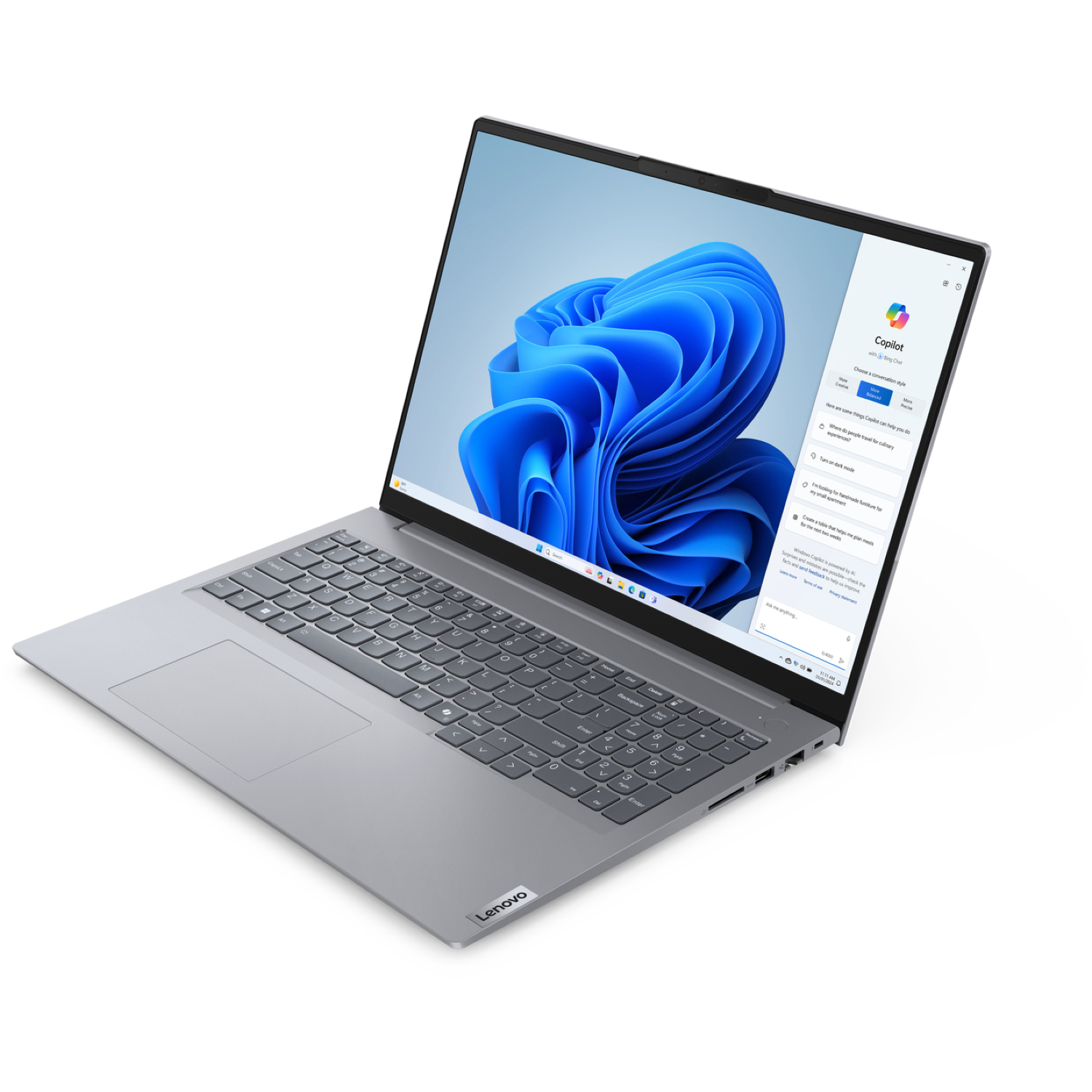 A silver Lenovo laptop is open, displaying a blue abstract image on the screen. The Copilot interface is visible.