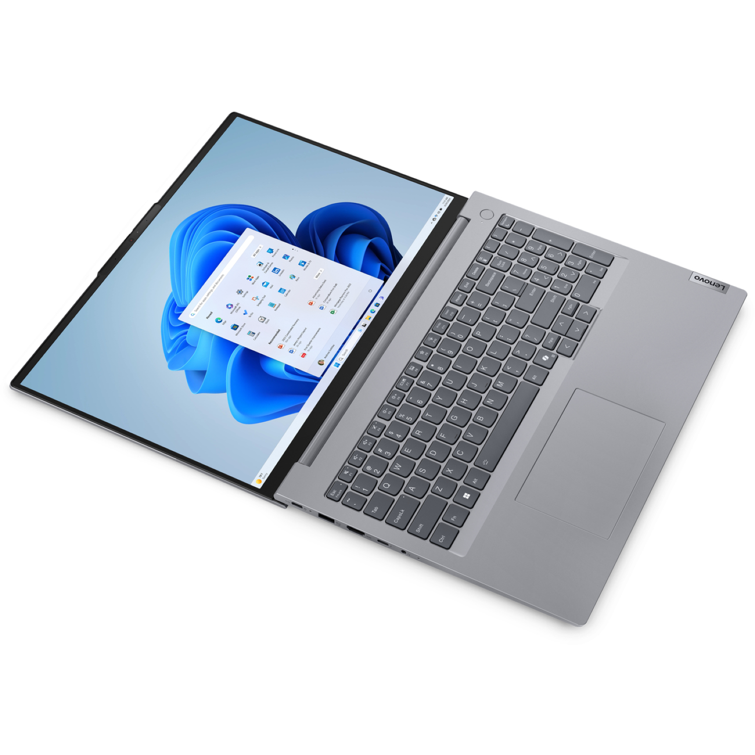 A Lenovo laptop is open, showing a Windows 11 interface with a blue floral wallpaper. The keyboard and touchpad are visible.