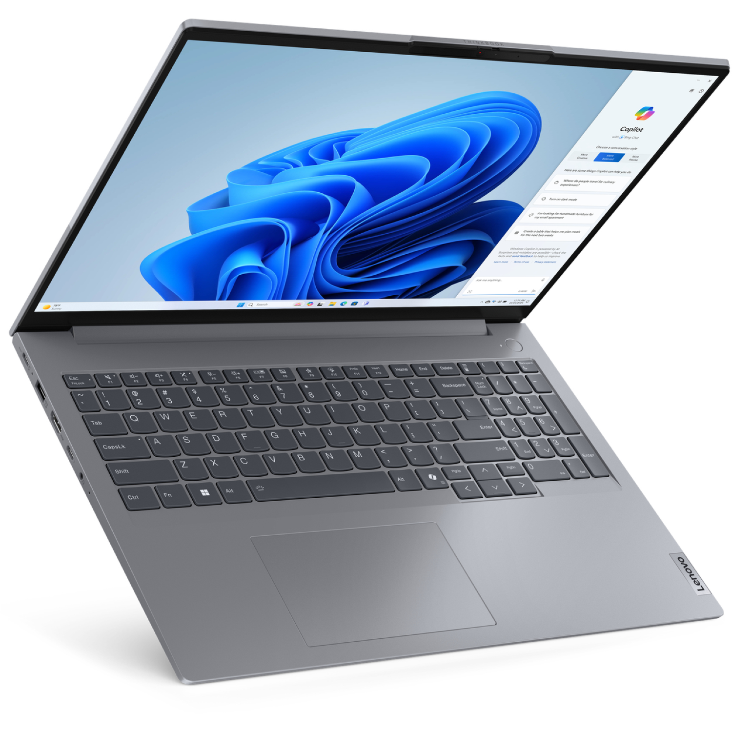 Gray Lenovo laptop open, showing keyboard and screen displaying a Copilot interface with blue abstract background.