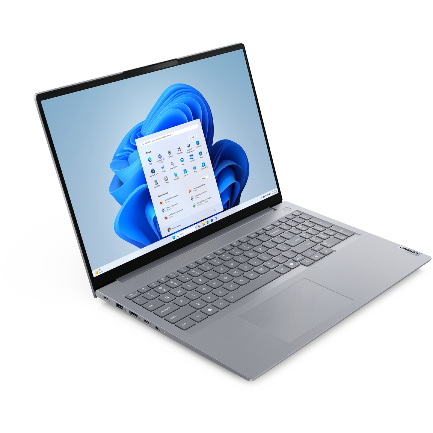A silver Lenovo laptop is open, displaying a Windows 11 interface with a start menu. The keyboard and trackpad are visible.