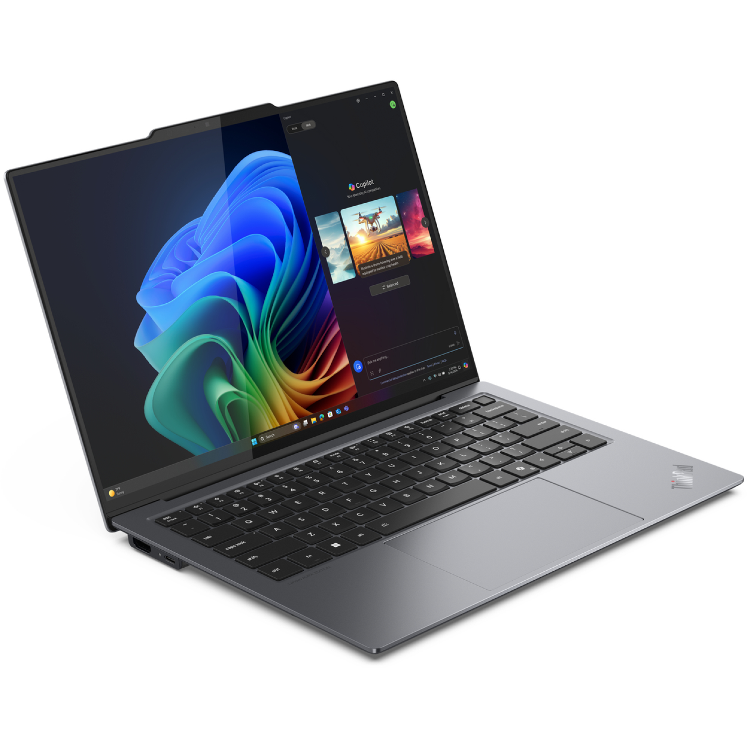 A gray laptop is open, displaying a colorful abstract image and a Copilot interface. The keyboard is visible, the background is white.