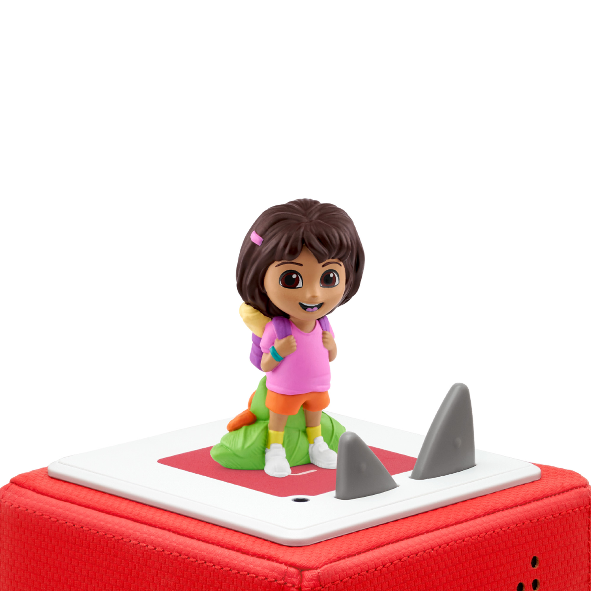 Eine Dora die Entdeckerin-Figur steht auf einer roten quadratischen Plattform mit grauen Haifischflossen. Weißer Hintergrund.