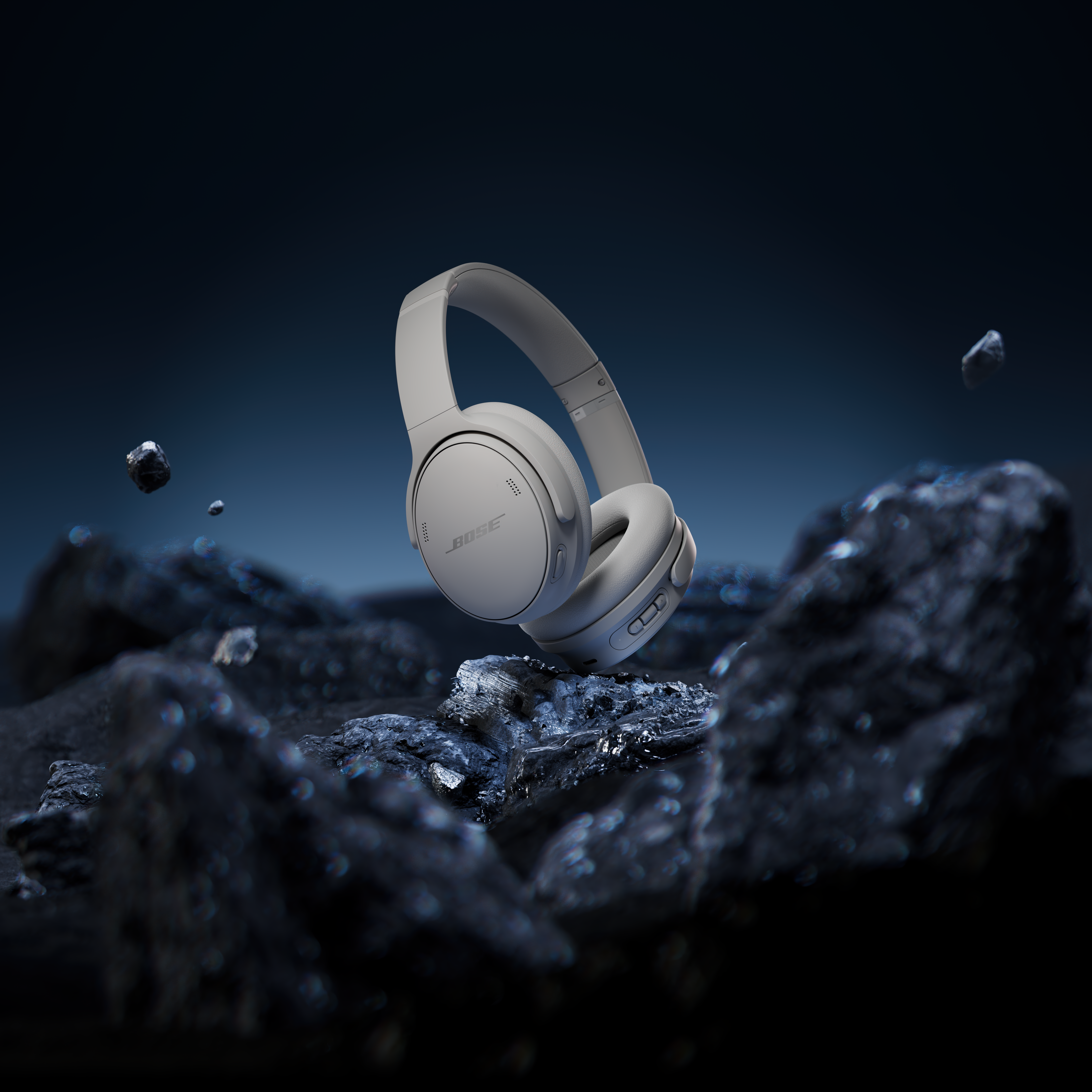 Casque Bose gris flottant au-dessus de roches sombres. Le fond est un dégradé bleu foncé.