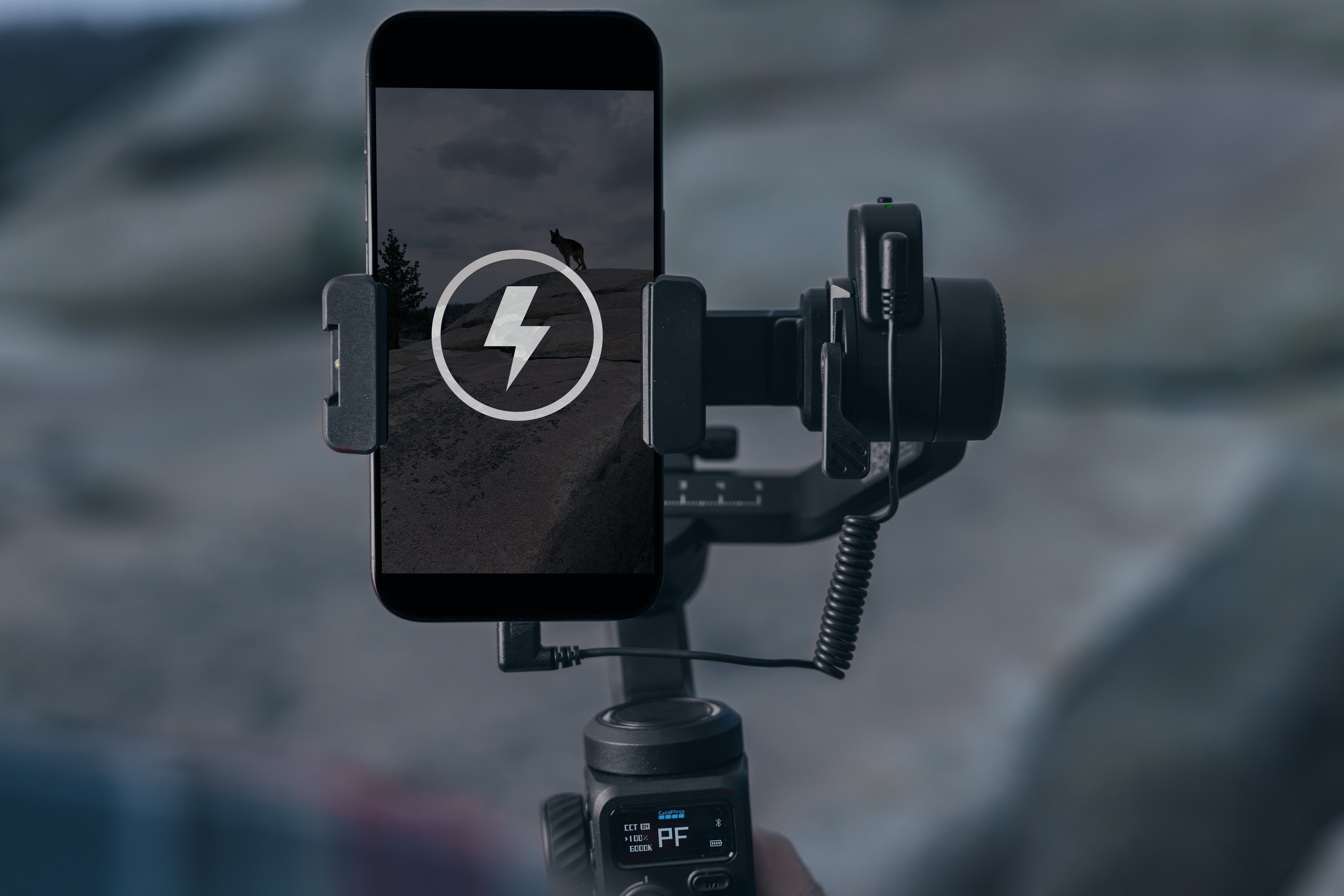 Ein Smartphone mit Blitzsymbol ist auf einem Gimbal montiert. Der Hintergrund ist verschwommen, mit einem Hauch von Natur.