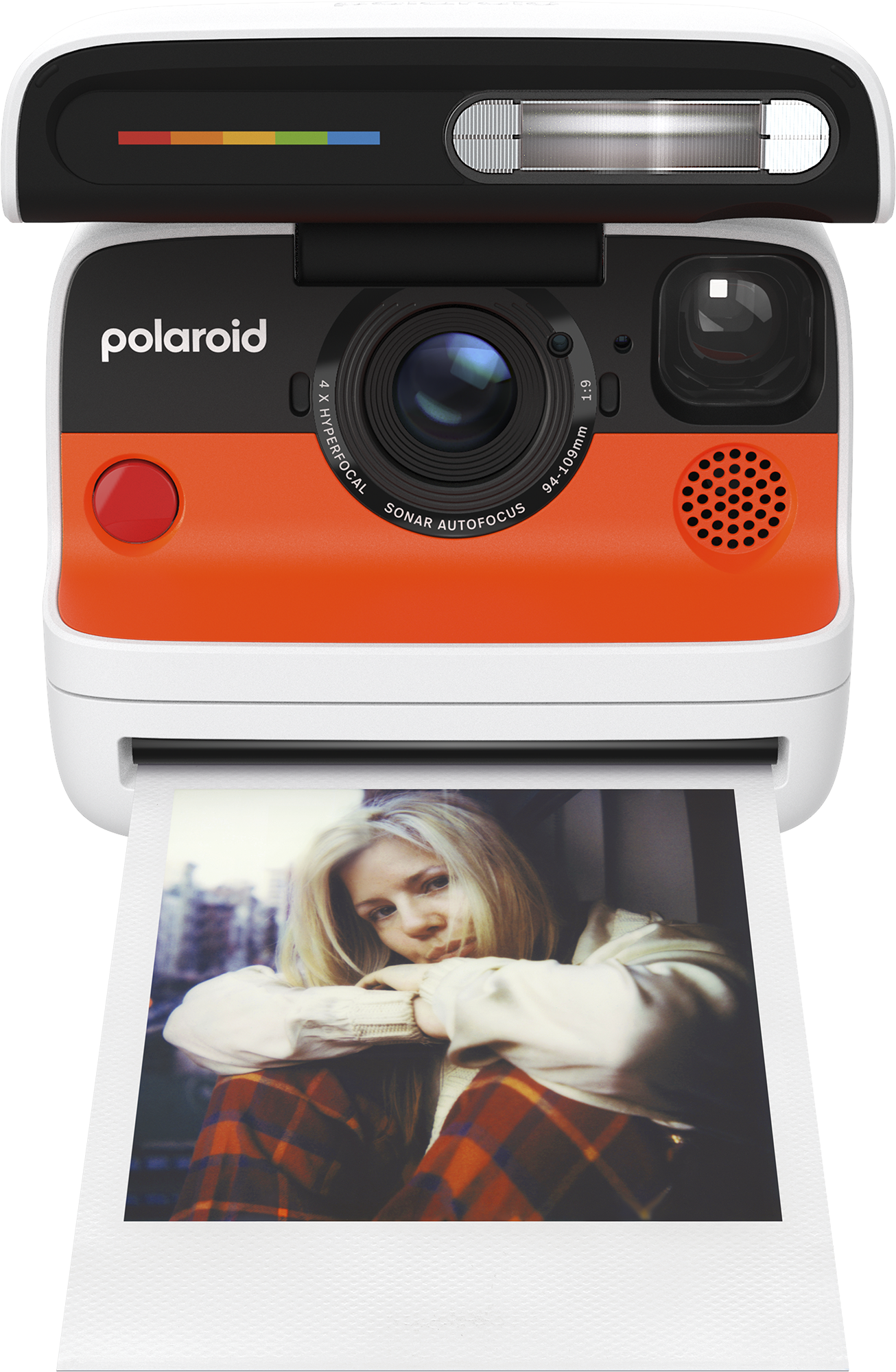 Polaroid fényképezőgép egy nő fotójával. A fényképezőgép narancssárga és fehér. A fotó egy nő kockás nadrágban és fehér ingben.