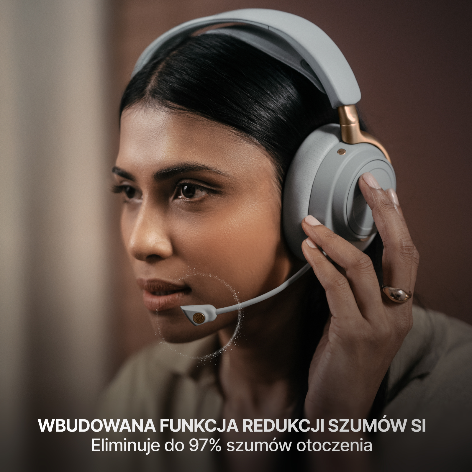 Kobieta w słuchawkach z mikrofonem. Dotyka zestawu słuchawkowego. Tło jest rozmyte i brązowe.